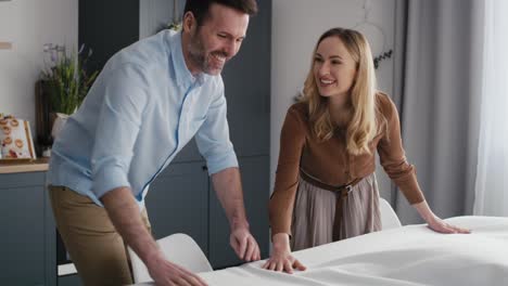 Pareja-Caucásica-Poniendo-Una-Mesa-Con-Un-Mantel-Blanco.