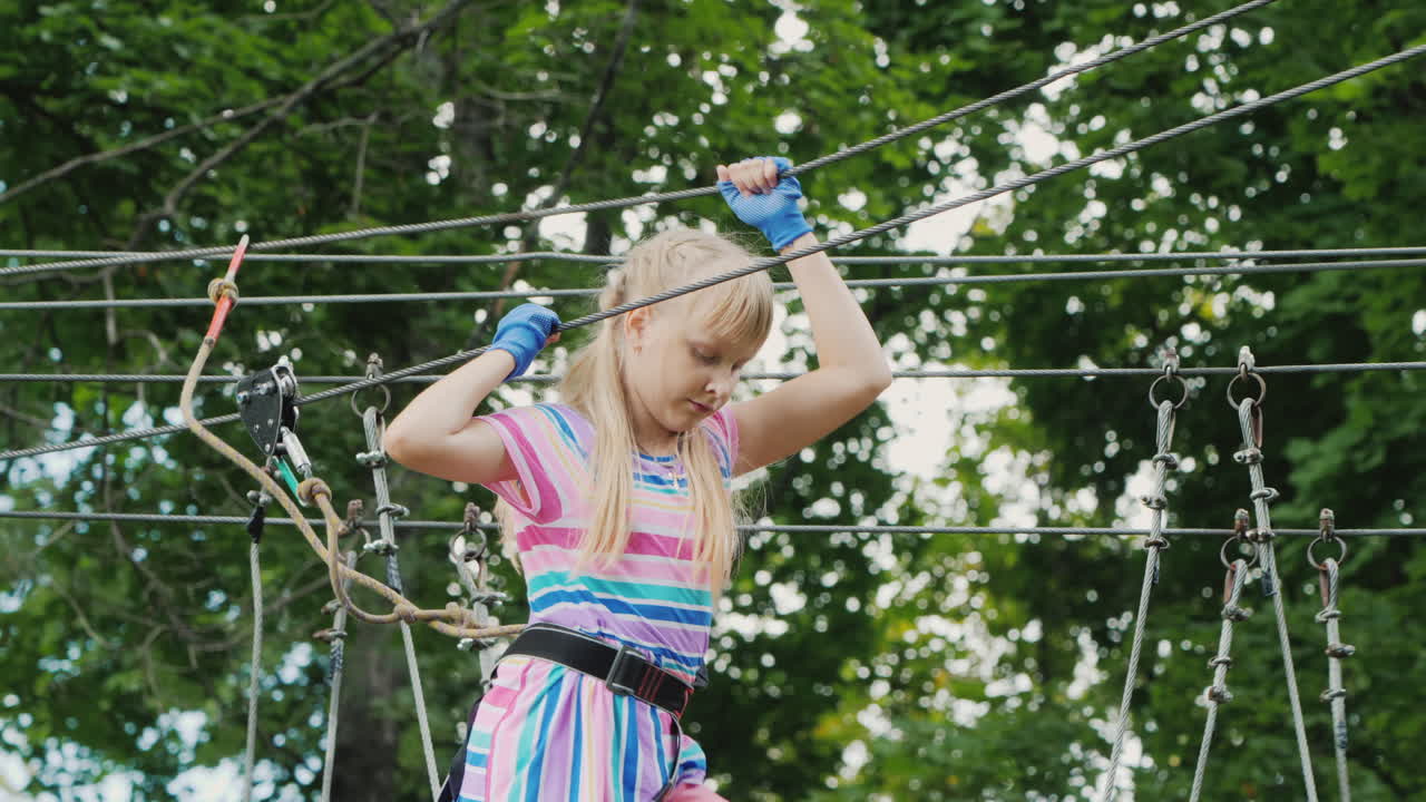 una chica valiente se mueve a lo largo de las cuerdas entre los árboles usa una cuerda de seguridad