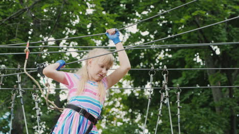 a brave girl moves along the ropes between the trees uses a safety rope