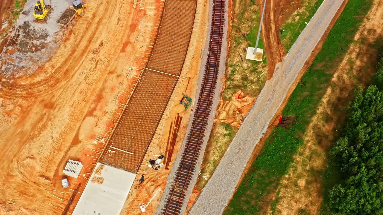 Excavator working with gravel beside curved railway line under construction