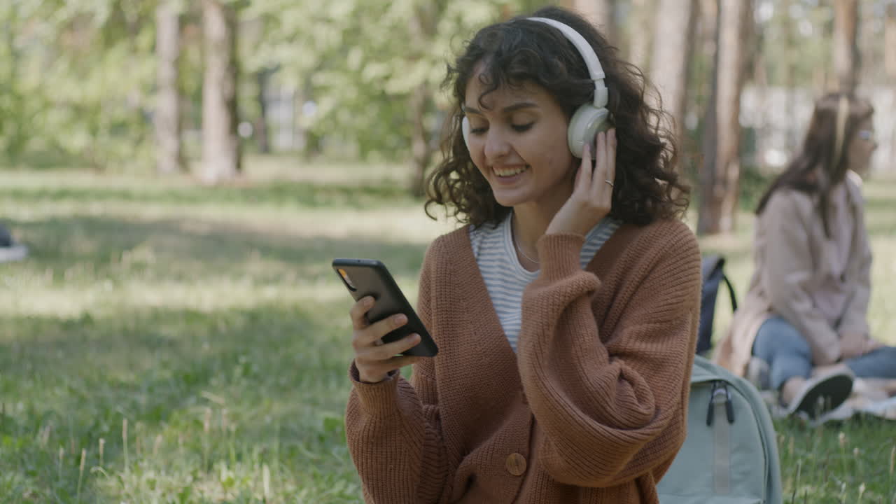 Young woman listening to music on headphones in a park