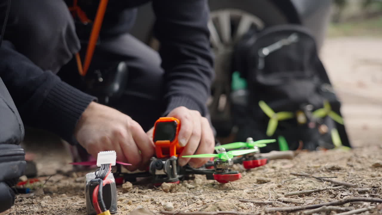 Person Assembling FPV Drone Outdoors on the Ground