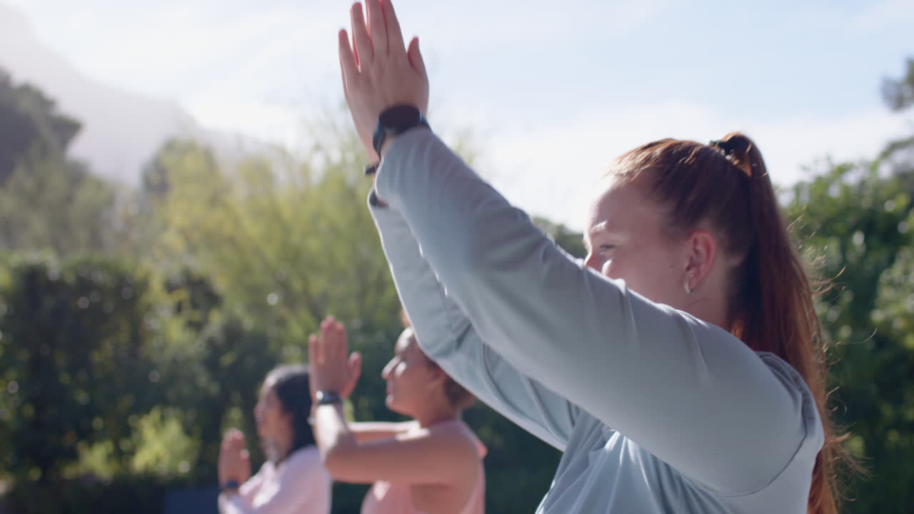 Practicing outdoor yoga, diverse female friends raising arms and enjoying nature