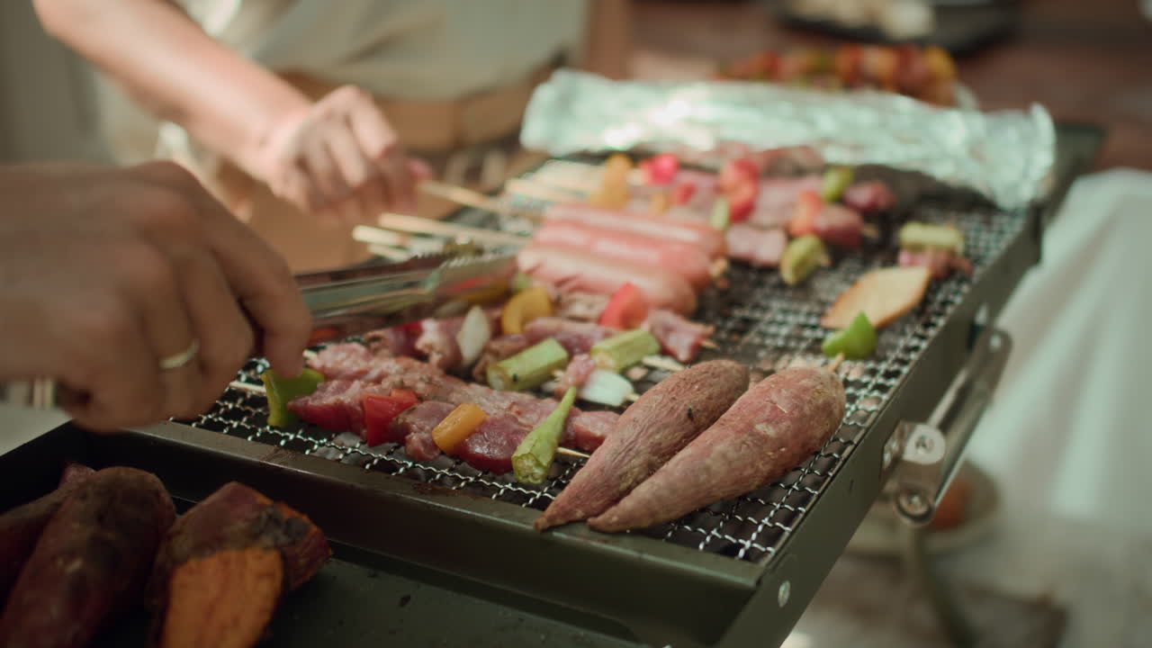 Hands of People Barbecuing Sausages and Vegetables