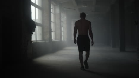 muscular athlete walking in crossfit gym. man going in sport club for training