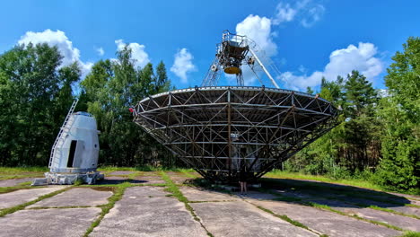large radio telescope dish in a forest clearing