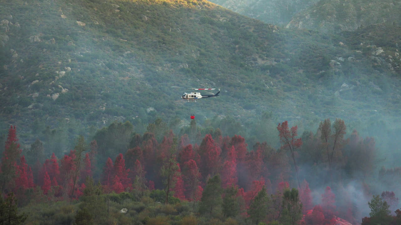 Elicottero che sgancia ritardante chimico rosso per prevenire la propagazione di incendi boschivi