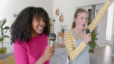 happy diverse teenage female friends dancing and singing at home, slow motion