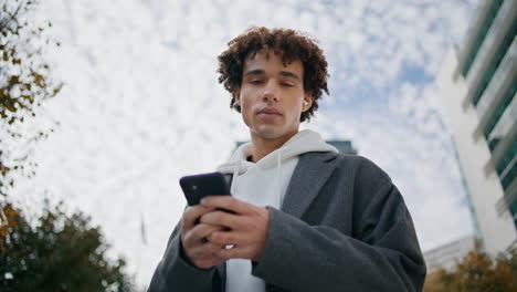 young man using phone outdoors portrait. earphones teenager listening music