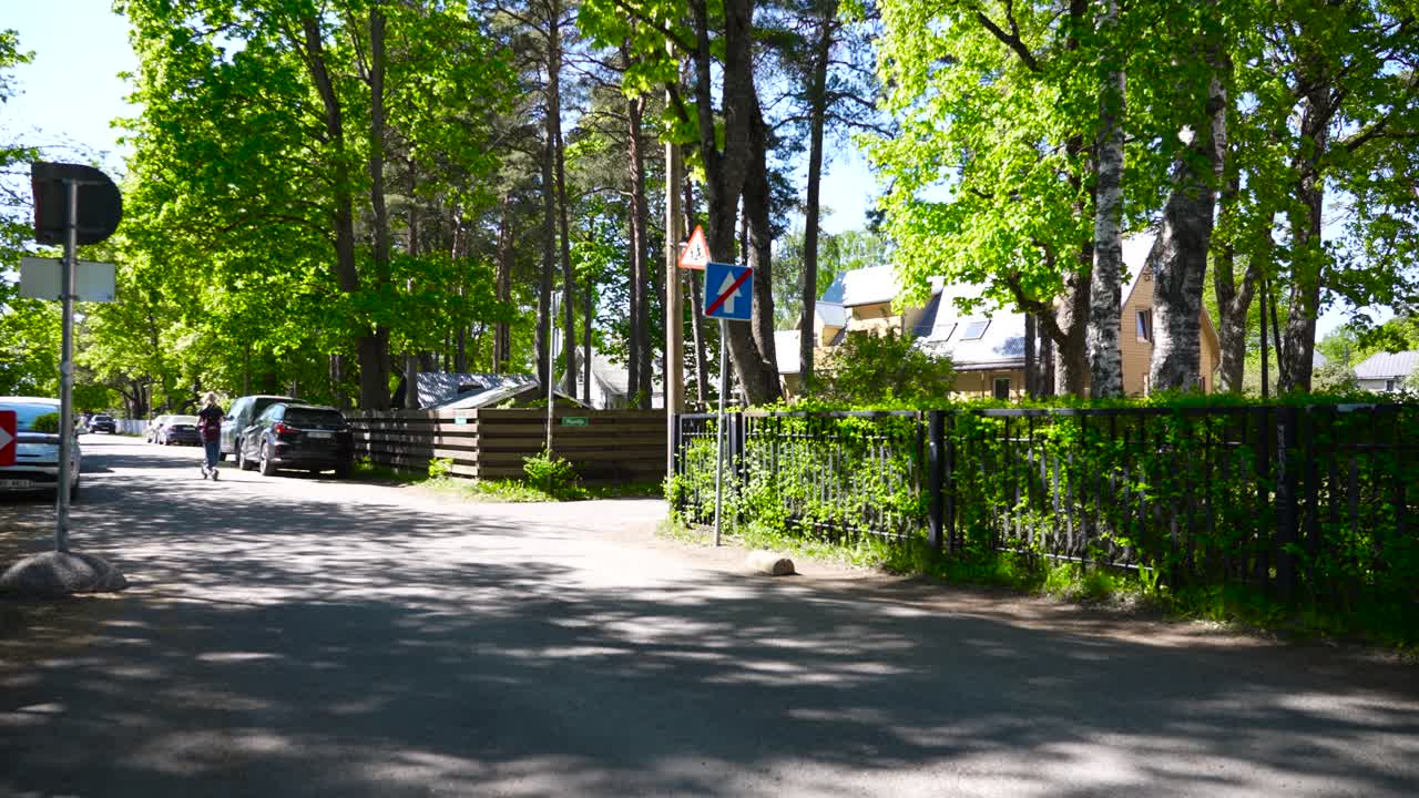 Footage of a street in Estonia with a one way ending traffic sign that has is blue and has a crossed out white arrow on it. Filmed in Nõmme in Raudtee and Puuvilja street. Summer time sun shining.