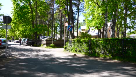 footage of a street in estonia with a one way ending traffic sign that has is blue and has a crossed out white arrow on it. filmed in nõmme in raudtee and puuvilja street. summer time sun shining.