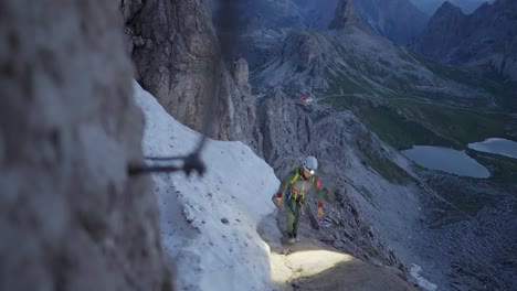 alpinista femenina con faros y equipo de escalada en una "via ferrata" en los dolomitas