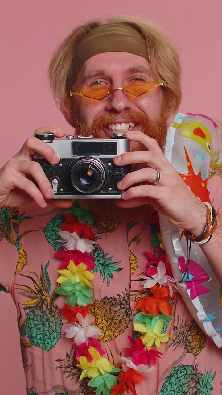 Giovane uomo felice, fotografo turista, che scatta foto con una macchina fotografica retrò e sorride in vacanza.
