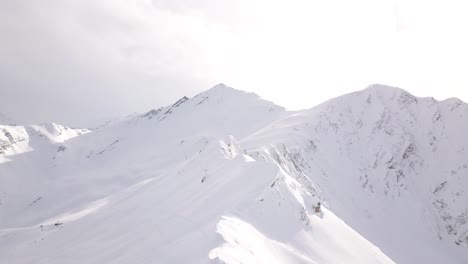 Aerial-drone-view-of-a-snowy-mountain-peak-and-mountains-chain-during-winter