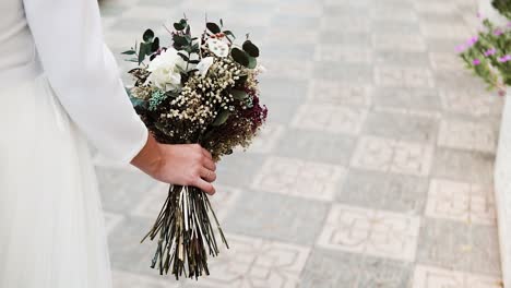 Novia-Elegante-Caminando-En-La-Calle-Sosteniendo-Un-Hermoso-Ramo-De-Flores