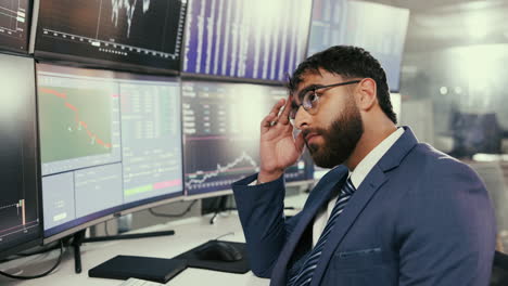 a businessman looking worried at charts on multiple computer screens