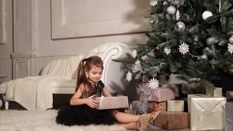 girl opening christmas presents under the tree