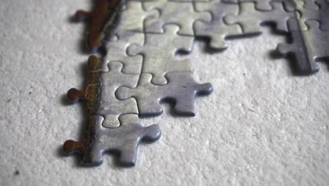 man places small pieces of a puzzle, close up shot 4k