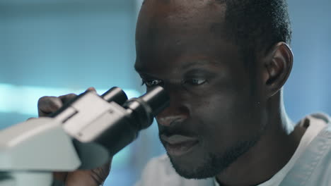 black scientist using microscope in lab