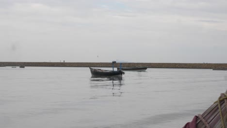 Dolly-Revela-A-La-Izquierda-Un-Pequeño-Bote-Vacío-Que-Flota-En-Las-Aguas-Del-Puerto-De-Gwadar,-En-La-Costa-De-Baluchistán