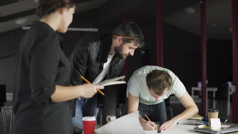 Young-architects-working-on-a-project,-drawing-and-thinking-in-modern-office.-Young-woman-taking-notes.-Shot-in-4k.