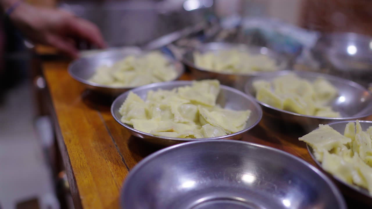 Several small metal bowls filled with fresh ravioli for bagna cauda on wooden table