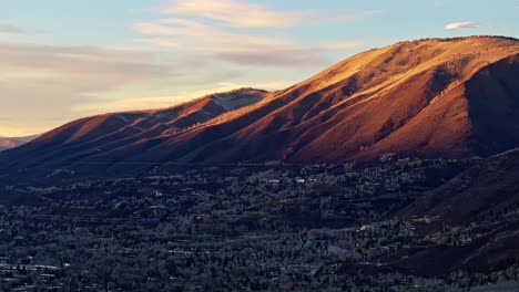 sunset glow illuminates peaks and frosty treetops in soft golden mountain panorama, aerial backdrop background