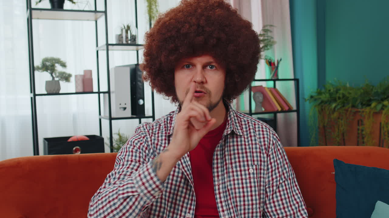 Young man presses finger to lips makes silence hush sign do not tells gossip secret, quiet at home