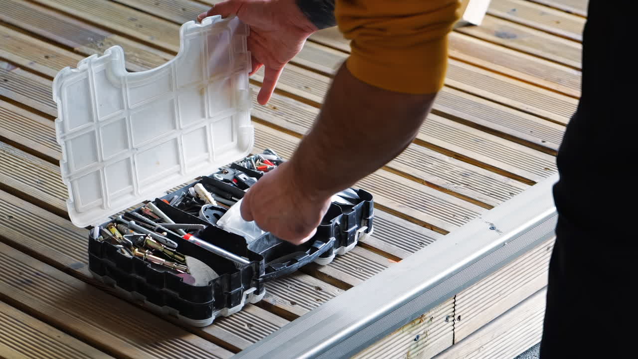 A man choosing a thing in box with multiple different screws and instruments