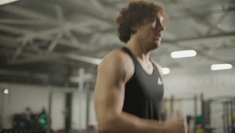 muscular man running on treadmill during training session in gym