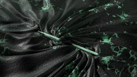 green needle on wrinkled dark fabric