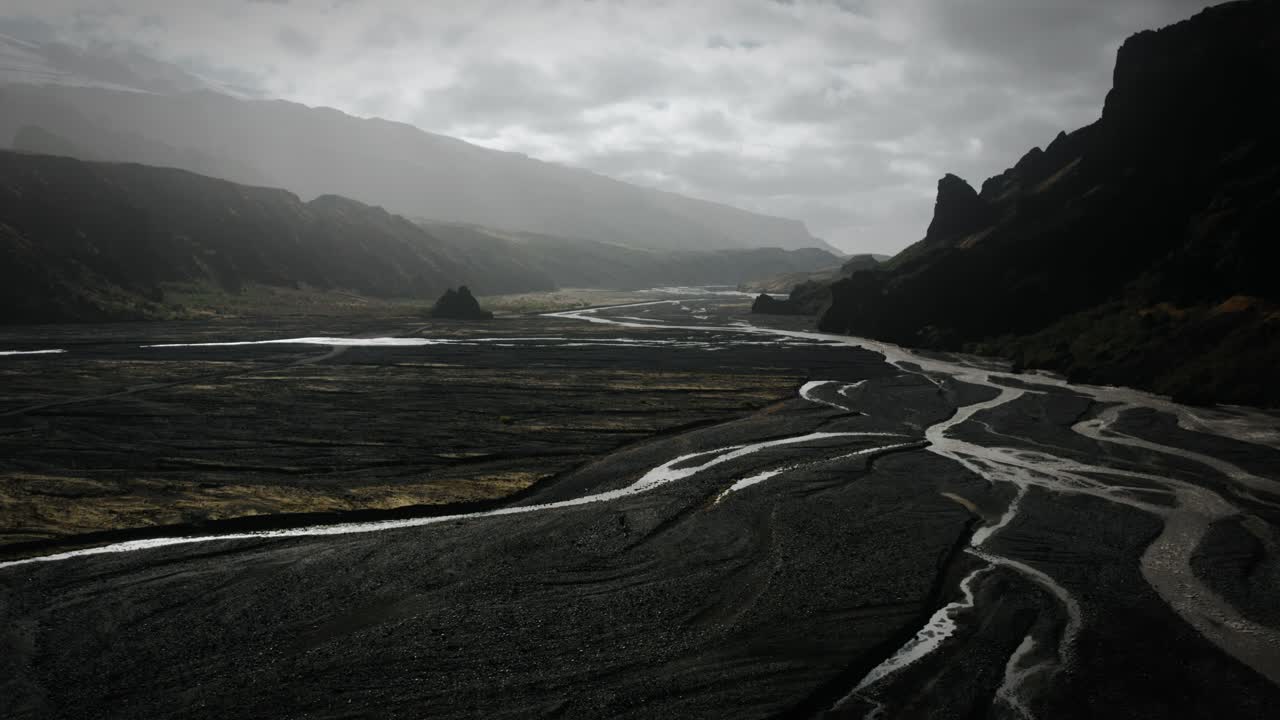 Dramatic aerial thor valley, glacial river flowing through black volcanic scenery, thorsm&ouml;rk national park Iceland