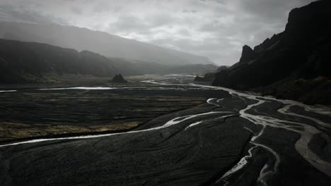 dramatic aerial thor valley, glacial river flowing through black volcanic scenery, thorsmörk national park iceland