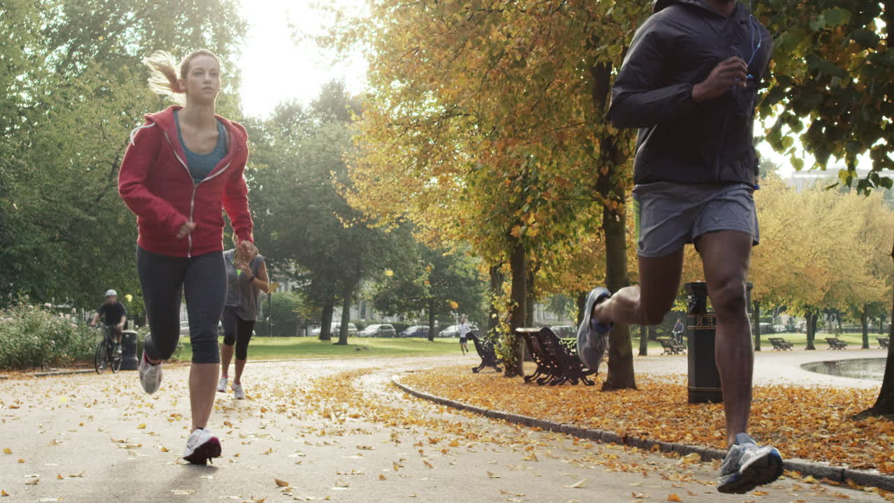 Gruppo di runner che corrono nel parco indossando tecnologia indossabile e dispositivi connessi.