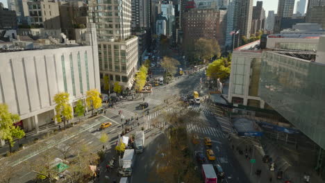 Forwards-fly-above-Broadway.-Tilt-down-on-pedestrians-crossing-road-at-crossroad.-Cars-passing-intersection.-Manhattan,-New-York-City,-USA