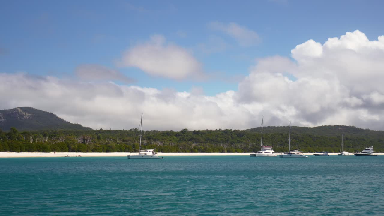 Spiaggia incontaminata di Whitehaven sotto un cielo azzurro e soleggiato mattutino, barche a vela, sabbia bianca purissima, Whitsundays Australia, Mar dei Coralli, crociera in barca, acqua calma, bassa e turchese, Isole Whitsunday, paesaggio della Grande Barriera Corallina.