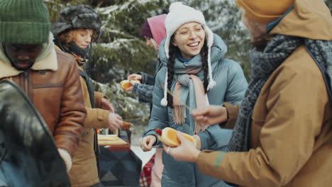 friends preparing hot dogs while camping in winter