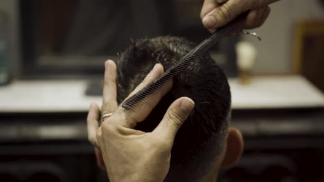 close up of barber cutting client's hair at barbershop