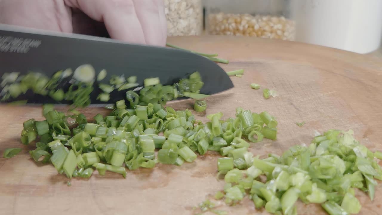 Slider Shot of Chopping Green Onions With a Chef's Knife on a Wooden Cutting Board