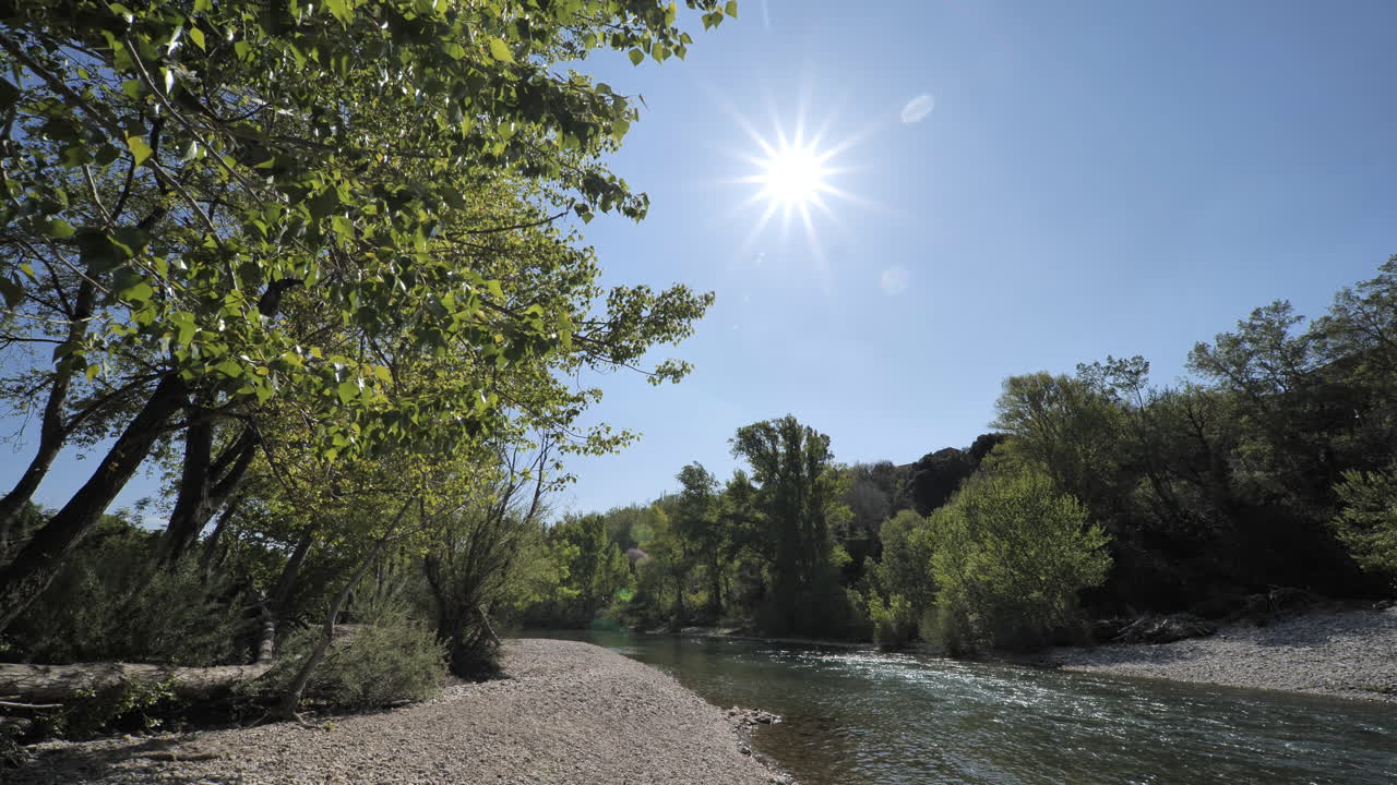 Sole e cielo blu lungo un fiume con alberi, Hérault, sud della Francia