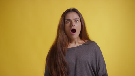 studio portrait of excited woman celebrating good news standing against yellow background 2