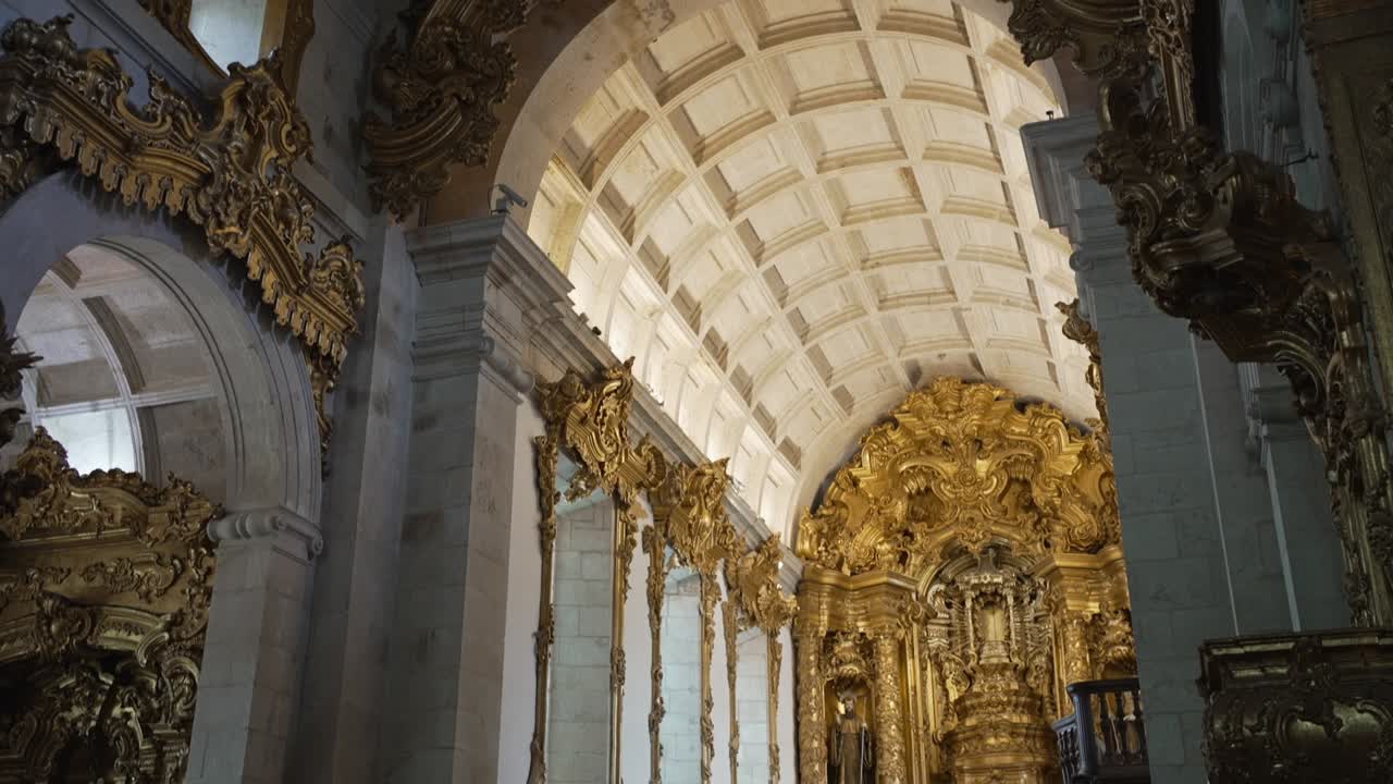 Interno sfarzoso di chiesa barocca con arco dorato e soffitto a volta