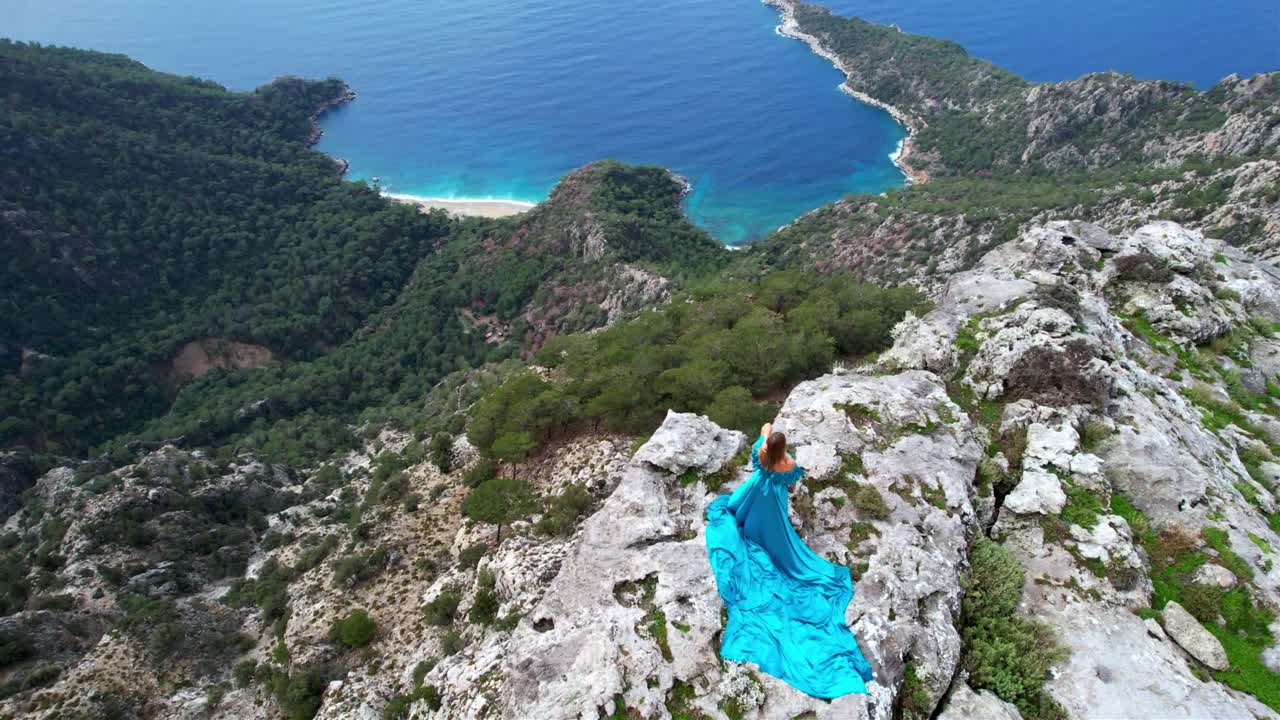 Woman in Blue Dress on a Clifftop Overlooking the Ocean