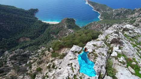 woman in blue dress on a clifftop overlooking the ocean