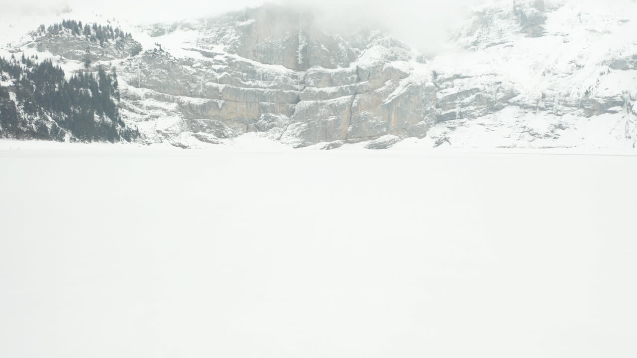 Moving low over snow covered ground with a large mountain in the background