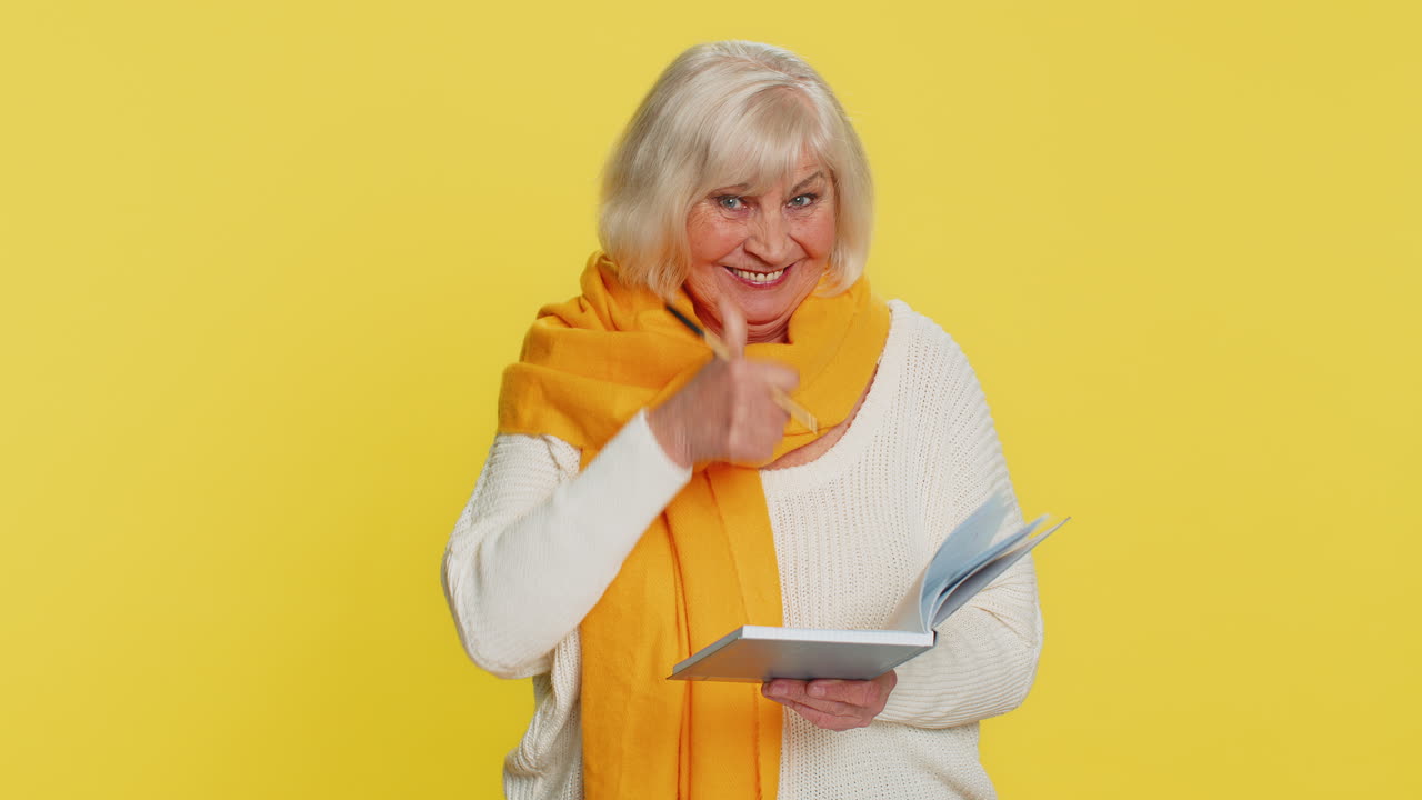 Thoughtful senior woman making notes writing down thoughts with pen into notepad notebook good idea