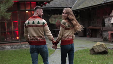 smiling couple coming closer to the country house. pair in similar clothes walking near the beautiful village manor.