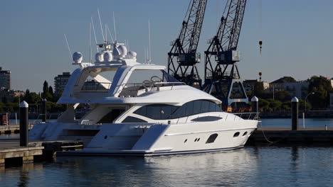 white yacht moored at dock with cranes