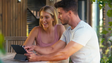 excited couple with credit card using digital tablet at home to book holiday or shop online