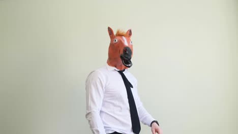 a funny man in a strange carnival horse mask is dancing and having fun a funny man in a strange carnival horse mask is dancing and having fun on a light background in the studio horse masquerade mask